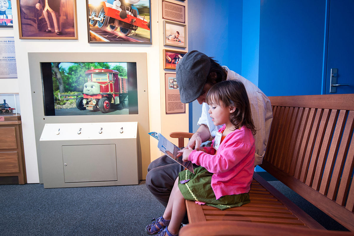 girl and father reading a book on a bench